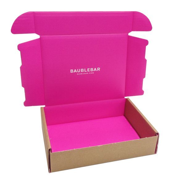 BaubleBar kraft exterior mailer box opening to bold hot pink interior with tissue paper